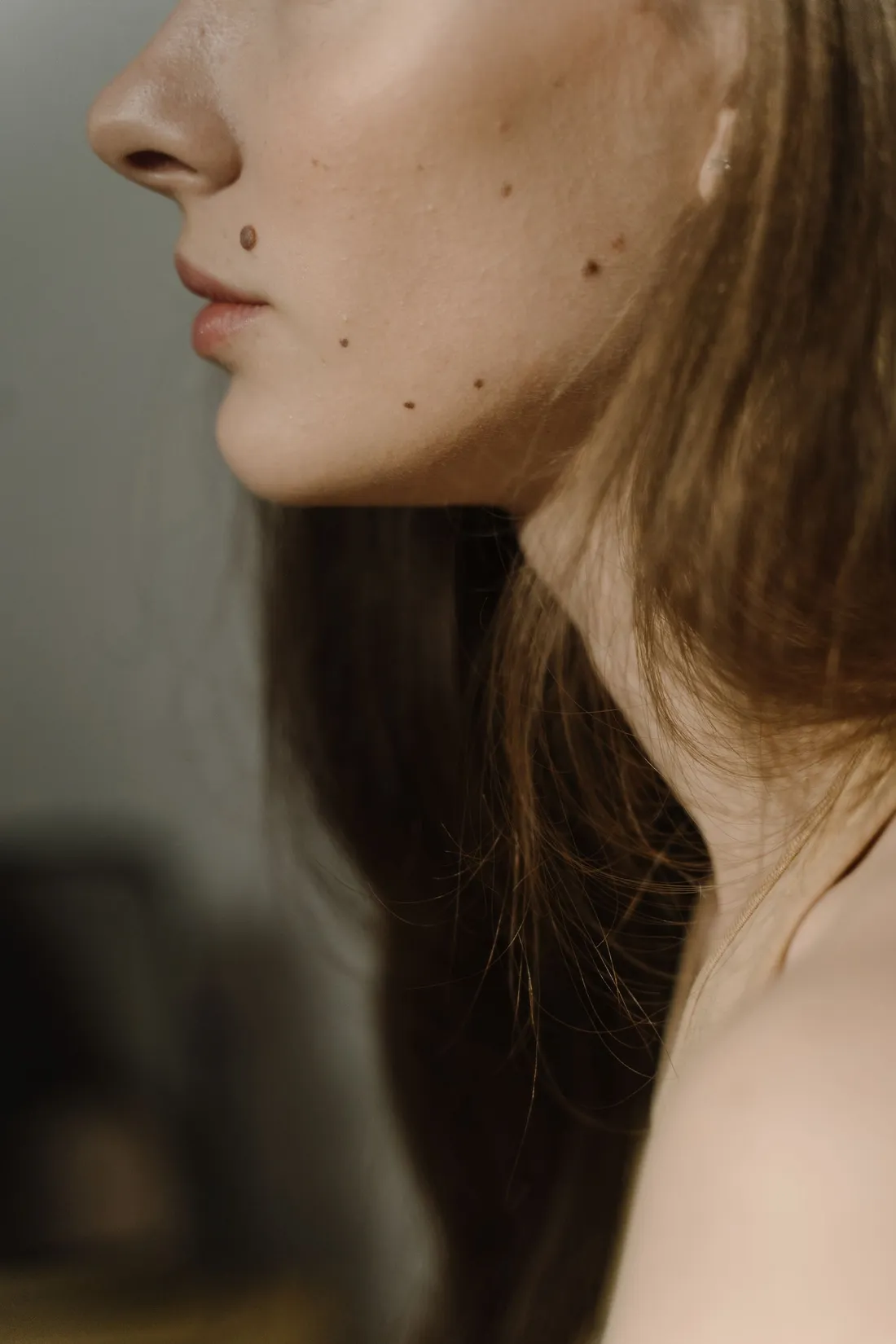 Side profile of a woman showing the chin and neck line in soft light
