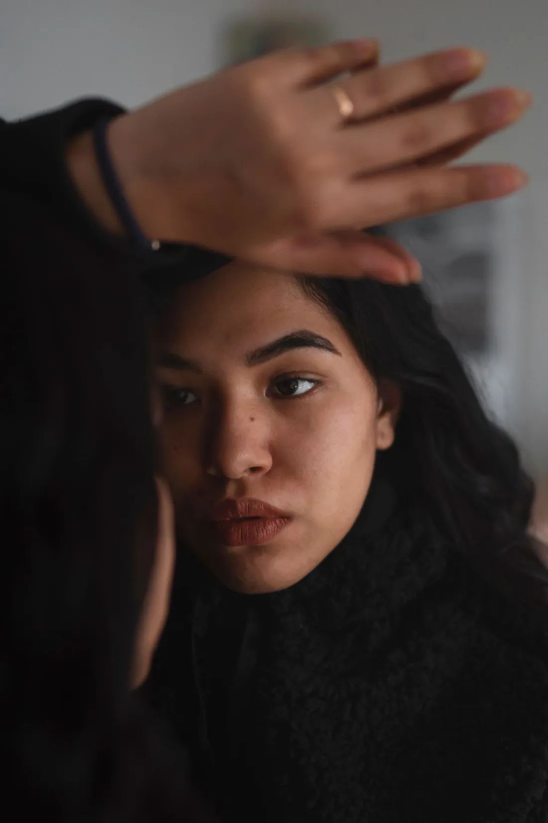 A woman touching her forehead while looking in a mirror