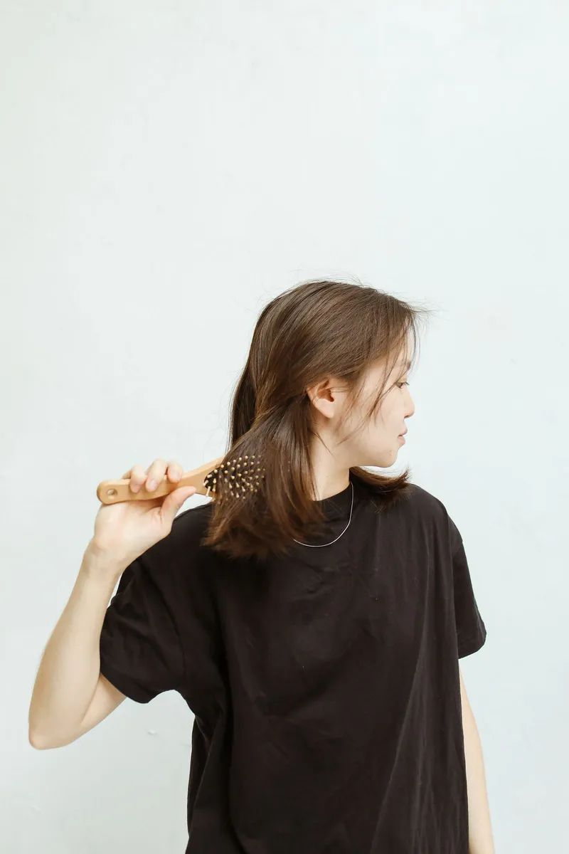 A woman brushing her hair in a bright, minimal room