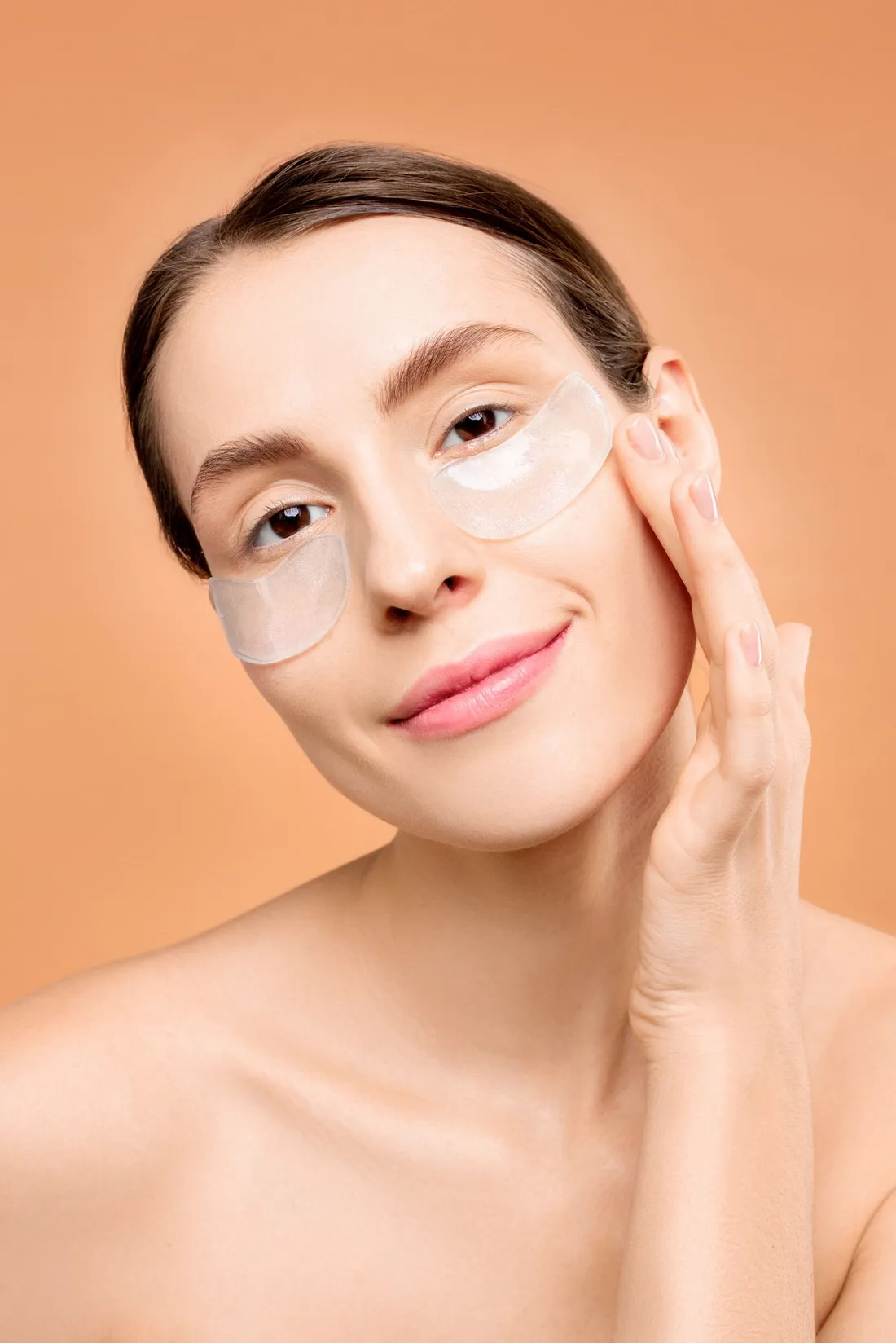 A woman applying under-eye skincare patches