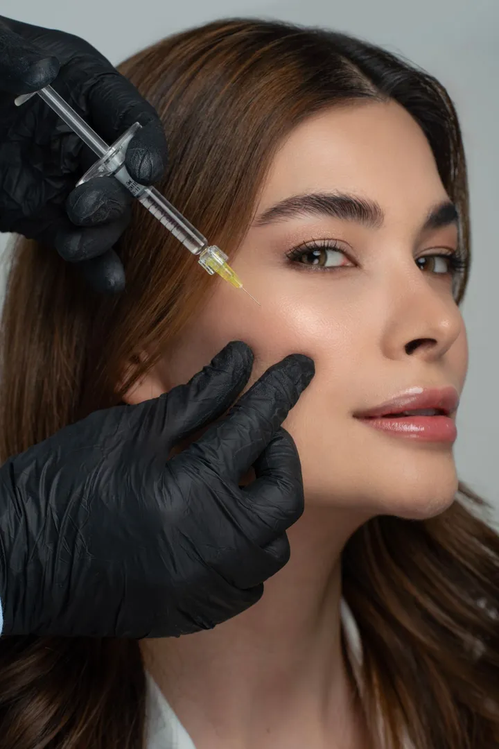 A facial filler treatment being administered by a gloved practitioner