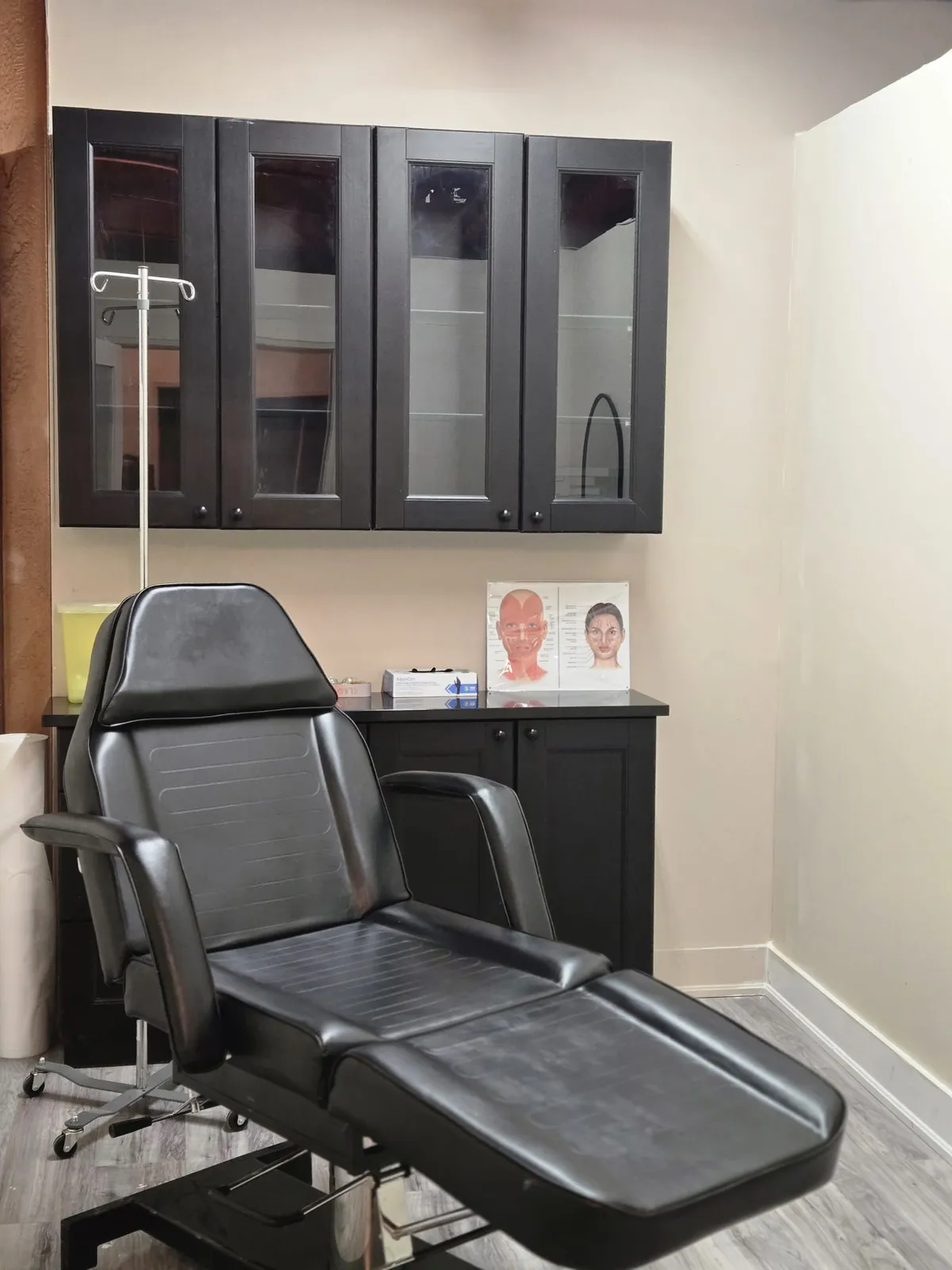 Treatment room with a black treatment chair at Chrysalis Beauté